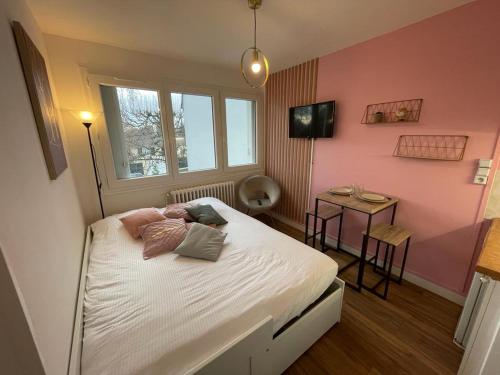 um quarto com uma cama num quarto cor-de-rosa em Studio proche centre ville em Caen