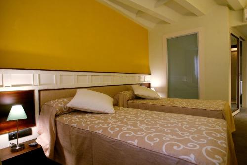 a bedroom with two beds and a yellow wall at Hotel La Fonda Moreno in Morella