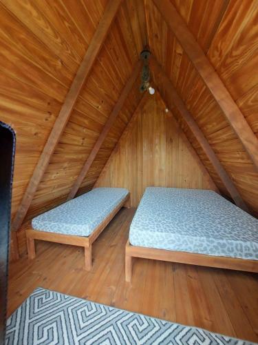 um quarto com 2 camas num sótão de madeira em Cabana com Ar condicionado e area de cozinha e banheiro compartilhado a 10 minutos do Parque Beto Carrero em Penha