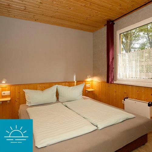 1 dormitorio con 2 camas y ventana en Bungalow SONNE UND MEER direkt am Strand en Dranske