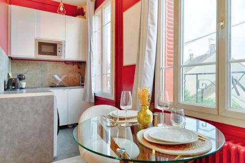 une cuisine avec une table en verre et des verres à vin dans l'établissement Studio Marie, à Vigneux-sur-Seine