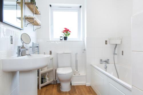 Baño blanco con lavabo y aseo en Cozy Townhouse in the heart of Greater Manchester, en Mánchester