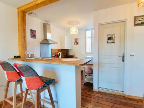 une cuisine avec un comptoir et deux tabourets de bar dans l'établissement Mignon et cosy à côté de la mer, à Mers-les-Bains