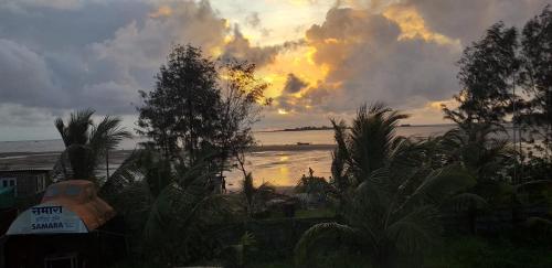 Blick auf einen Strand mit Sonnenuntergang im Hintergrund in der Unterkunft SAMARA SEAVIEW in Alībāg