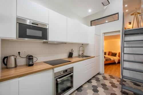 une cuisine avec des armoires blanches et un comptoir dans l'établissement NOTRE DAME, ODÉON 5e, Triplex 2 salles de bain, à Paris