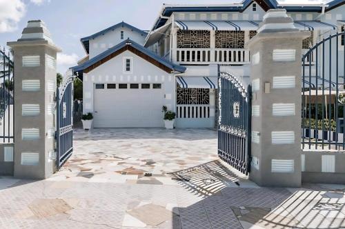a white house with a gate and a driveway at Joyful Ambiance Retreat in Bushy Park