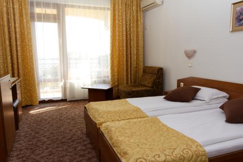 a hotel room with two beds and a chair and a window at Hotel Genada in Sveti Vlas