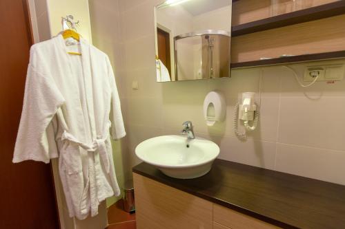 uma casa de banho branca com um lavatório e um espelho em Аполлонія em Poltava