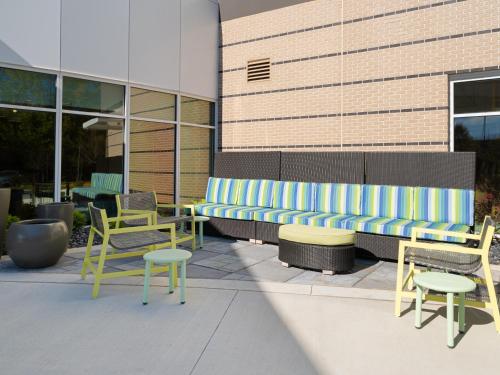 a bench with chairs and tables in front of a building at Home2 Suites By Hilton Atlanta Airport College Park in Atlanta