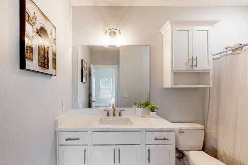 een witte badkamer met een wastafel en een spiegel bij The Primrose in Pensacola