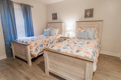 Duas camas num quarto com cortinas azuis em Marsh View Condo with an Indoor Pool Hot Tub em Myrtle Beach