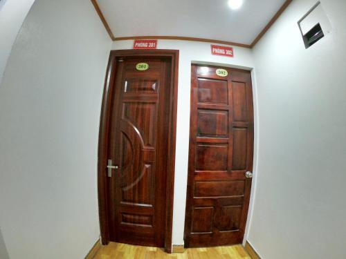 two brown wooden doors in a room with white walls at Minh Hưng Hostel in Sa Pa