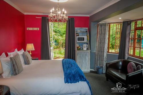 a bedroom with red walls and a bed and a chair at Gypsy Guest House Clarens in Clarens
