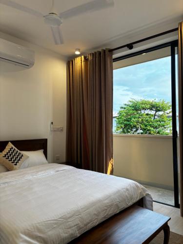 a bedroom with a bed and a large window at Sea Esta Villa Mount Lavania in Ratmalana