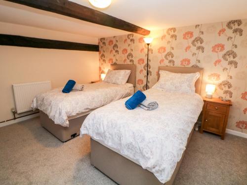 1 dormitorio con 2 camas con almohadas azules en Wilson Eyre Cottage, en Castleton