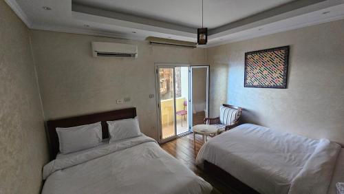 1 dormitorio con 2 camas y una ventana con puerta en Simple sea view apartment - families only, en Alejandría