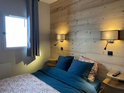 - une chambre dotée d'un mur en bois avec un lit et deux lampes dans l'établissement appartement le Chamois 312 Valmeinier 1900 piscine extérieur uniquement ouverte saison d été avec 1 chambre, à Valmeinier