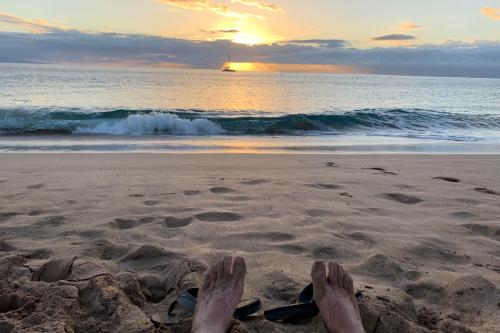 Eine Person sitzt am Strand und hat die Füße im Sand. in der Unterkunft Panoramic Ocean View Home in Elk with Beach Access in Elk