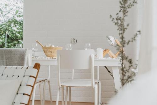 ein weißes Esszimmer mit weißen Stühlen und einem Tisch in der Unterkunft Design Holiday Home in Ermelo