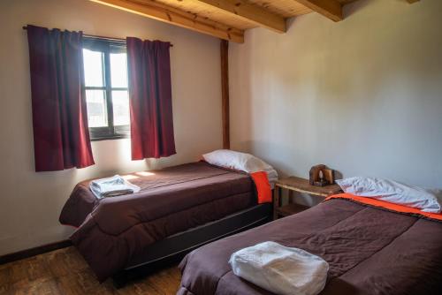 a room with two beds and a window in it at Lupulito Lodge Cabañas de Montaña in Ciudad Lujan de Cuyo