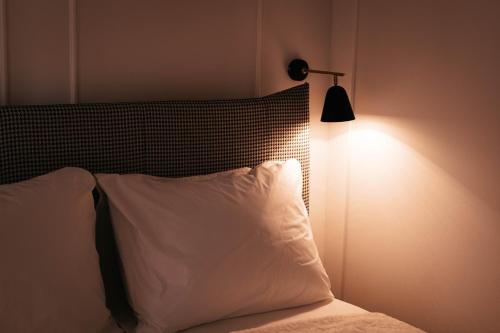 a bed with a white pillow and a lamp at Luxury Jacuzzi Apartment in Mostar