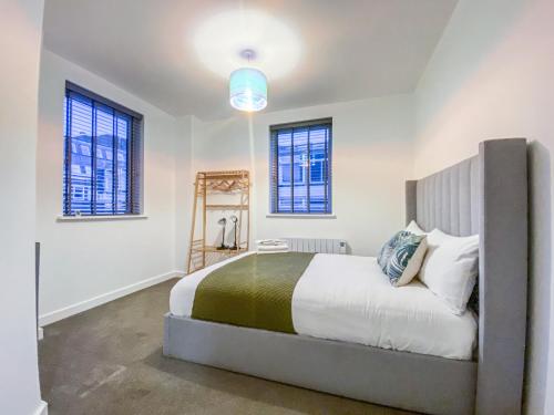 - une chambre avec un lit et 2 fenêtres dans l'établissement Cathedral View Apartments by Elegance Living, à Peterborough