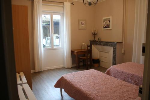 a bedroom with two beds and a fireplace and a window at Maison Hormidas in Crouseilles