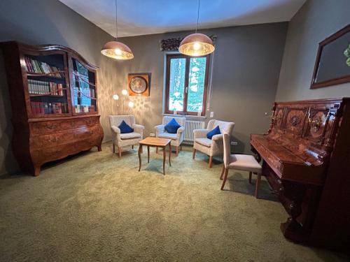 a living room with a piano and chairs and a table at hideauts hotels Der Rosengarten in Füssen