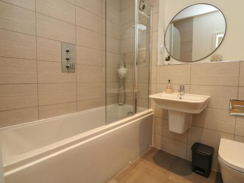 a bathroom with a tub and a sink and a mirror at Harley's Hideaway in Appledore