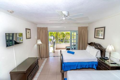 a hotel room with two beds and a balcony at Savannah Beach Club Hotel & Spa in Bridgetown