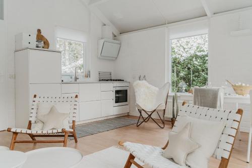 a kitchen with white cabinets and chairs in a room at Design Holiday Home in Ermelo