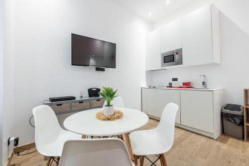 une cuisine blanche avec une table et des chaises blanches dans l'établissement Garibaldi Square - Cozy 1 Bdr Old Town, à Nice