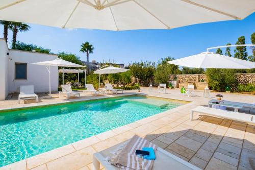 - une piscine avec des chaises et des parasols dans la cour dans l'établissement Villa VentoSolare Luxury - Specchia, à Specchia