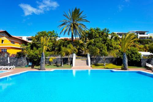 een groot zwembad met palmbomen en een gebouw bij Casa Bellavista - Pueblo Don Thomas in Playa de Santiago
