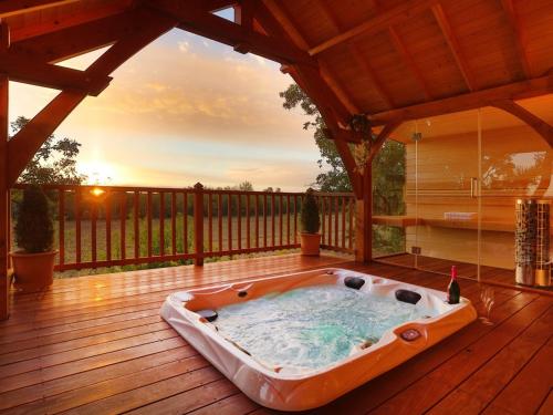 bañera de hidromasaje en la cubierta de una casa en Cabane de Prestige avec Jacuzzi et Sauna privatifs, en Alzonne