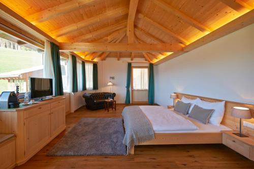 Exclusive Chalet Grumer 700 sqm في سوبرابولسانو: غرفة نوم بسرير وتلفزيون في غرفة