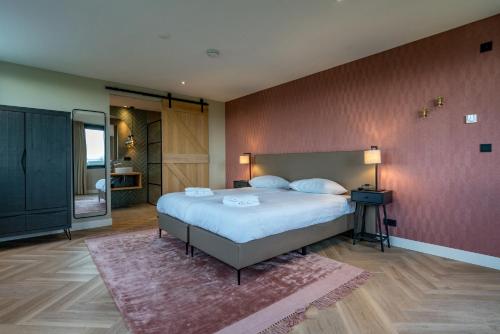 1 dormitorio con 1 cama grande y pared roja en Vakantiewoning De Princenhof, en De Cocksdorp