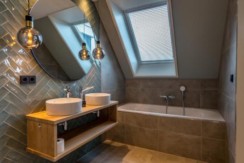 a bathroom with two sinks and a tub and a mirror at Vakantiewoning De Princenhof in De Cocksdorp