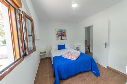 una camera da letto con un letto con lenzuola blu e una finestra di Apartamento BORA a Morro del Jable
