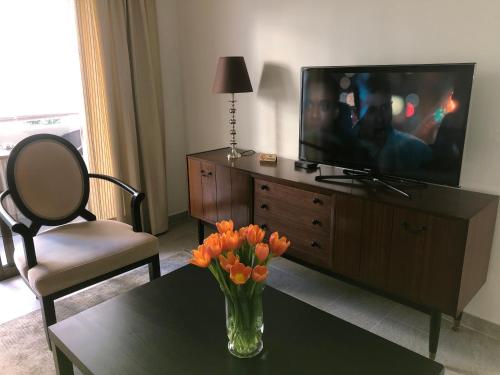uma sala de estar com um vaso de flores de laranja sobre uma mesa em T&L Apartments Germasogia em Limassol