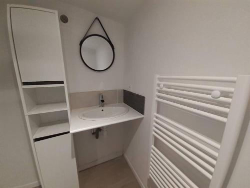 een witte badkamer met een wastafel en een spiegel bij Gîte La p'tite Maine in La Boissière-de-Montaigu