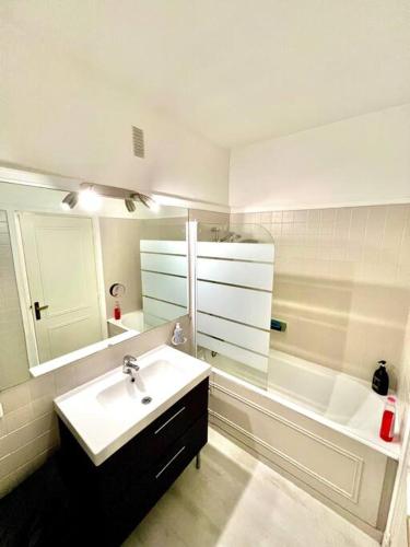 La salle de bains blanche est pourvue d'un lavabo et d'une baignoire. dans l'établissement Appartement au bord des berges + parking, à Toulouse