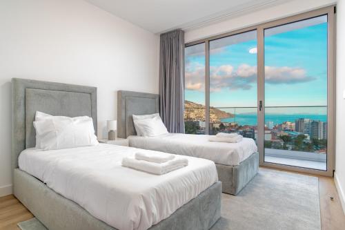 2 Betten in einem Zimmer mit einem großen Fenster in der Unterkunft The PLACE in Funchal
