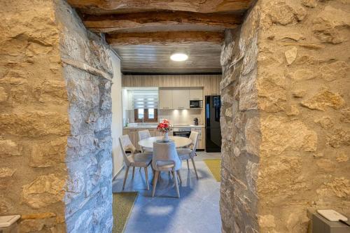 comedor y cocina con pared de piedra en Villa Ntora, en Xylopároikon