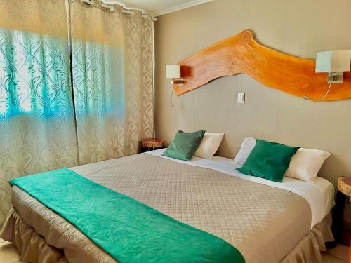 1 dormitorio con 1 cama con almohadas verdes y blancas en Tupa hotel iguazu en Puerto Iguazú