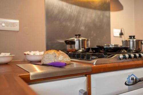 eine Küche mit einem Herd und einem Brotlaib auf einem Schneidebrett in der Unterkunft Minchin House, nr Npton Saints Rugby, sleeps 8 in Dallington