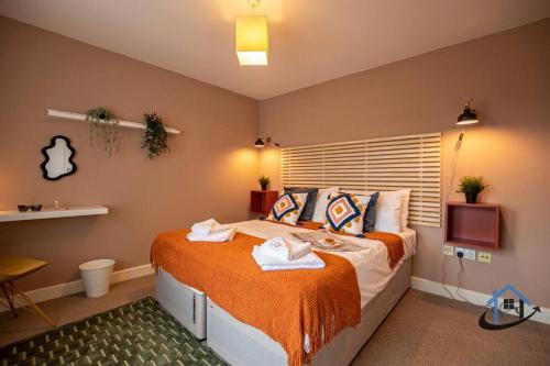 a bedroom with a large bed with orange sheets at Minchin House, nr Npton Saints Rugby, sleeps 8 in Dallington