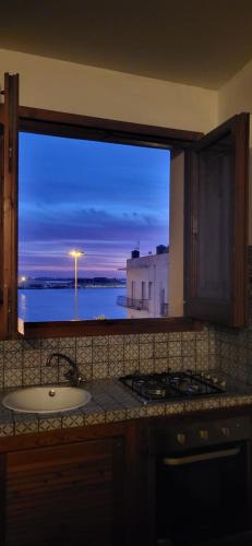 uma janela de cozinha com um lavatório e vista para o oceano em PerlaMarina em Trapani