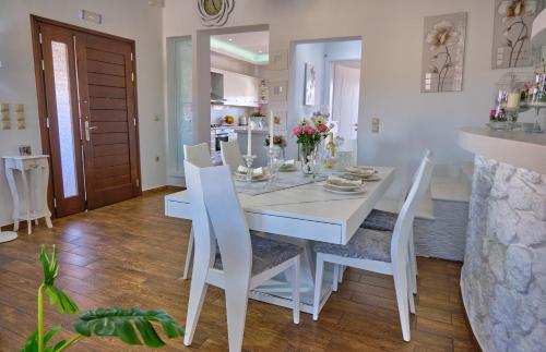 ein weißes Esszimmer mit einem weißen Tisch und Stühlen in der Unterkunft Elena Luxury Suite Agios Stefanos in Agios Stefanos