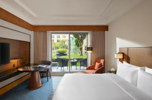 ムンバイにあるGrand Hyatt Mumbai Hotel and Residencesのベッド付きの客室とテーブル付きの客室を提供しています。